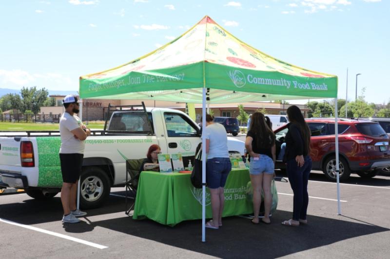 People under green informational tent in parking lot. 