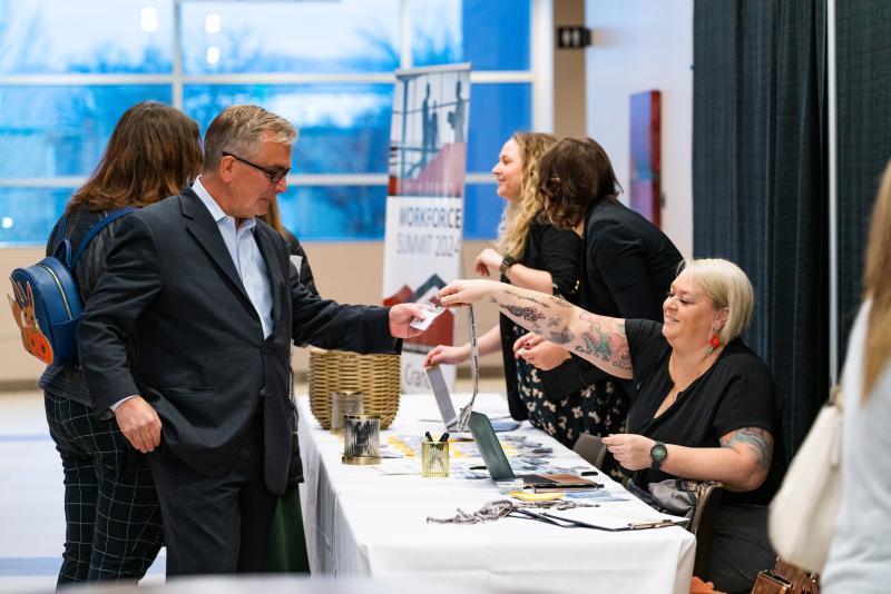 Two people checking into a conference and receiving name badges. 