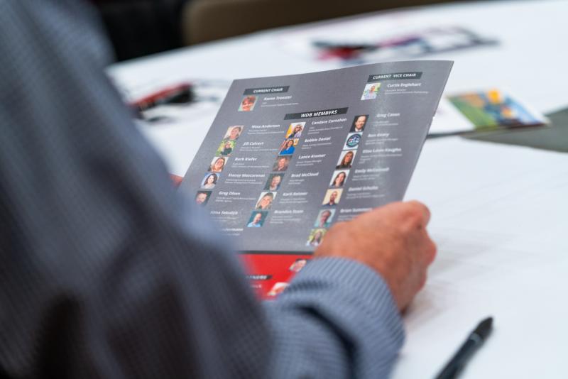 Man holding the event brochure with a page showing the key speakers scheduled.