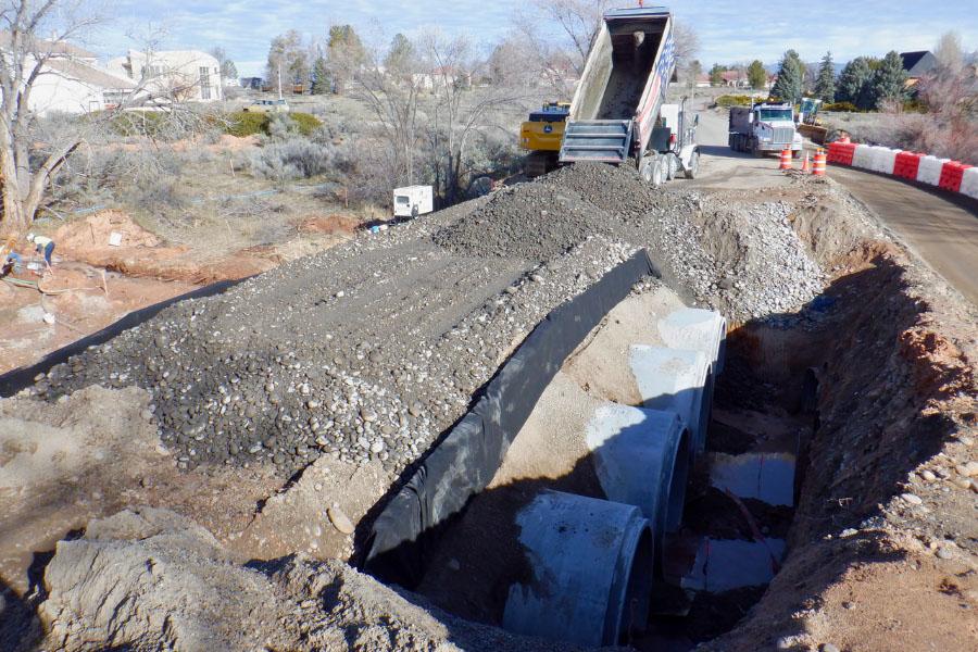 Construction truck dumping materials to backfill culverts.