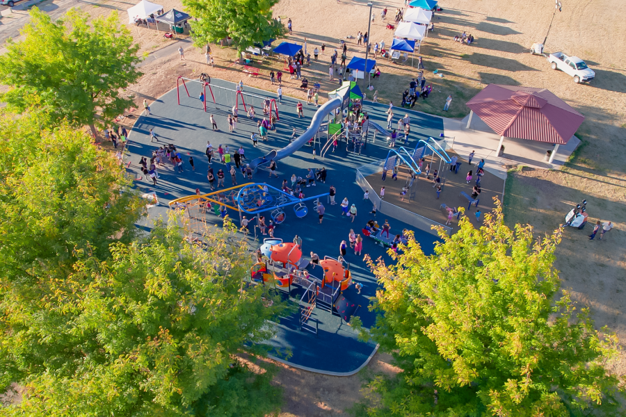 Aerial view of many kids and families gather at a park. 