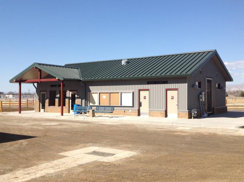 Photograph of the outside of the Show Office building with restrooms sign and two park benches out front