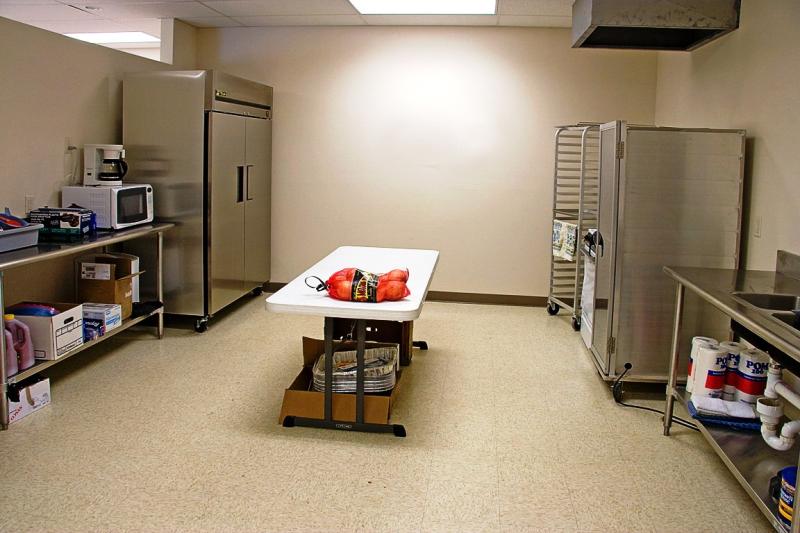 Photograph of the community building interior kitchen area with sink, refrigerator, microwave, and coffee pot