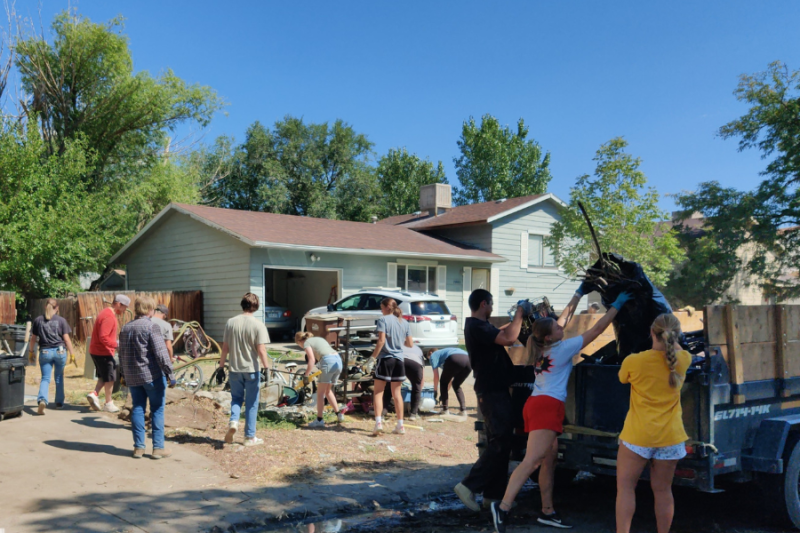 People cleaning up junk and trash outside of home. 