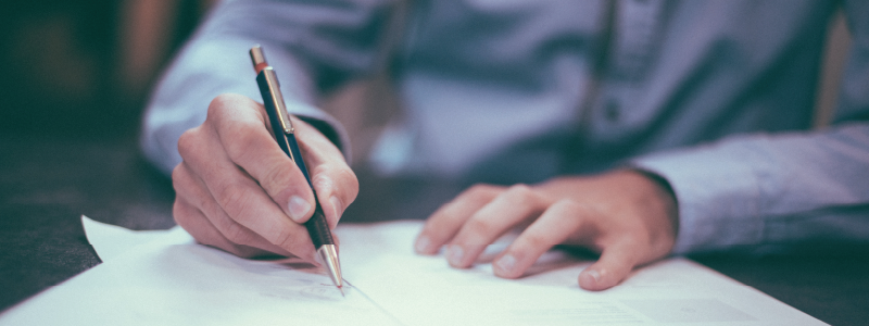 A person signs a pile of documents.