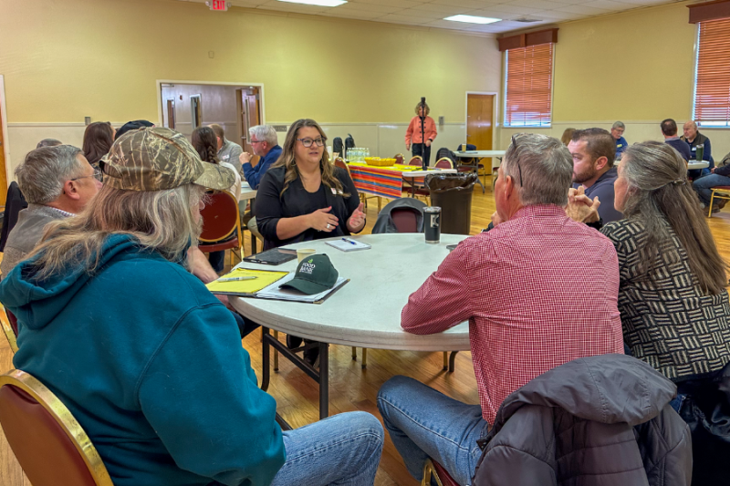 People sitting at a round table at a public meeting