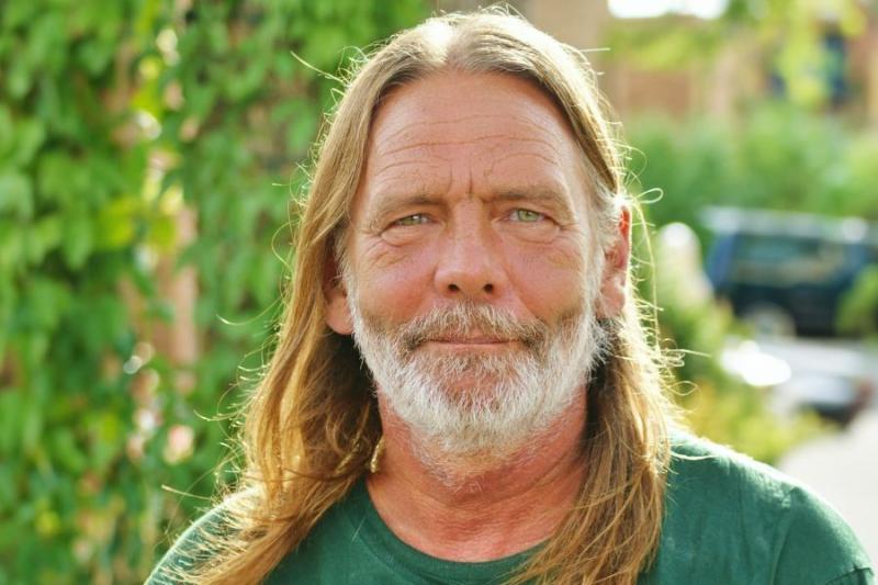 Headshot of man in green shirt (Bruce Lohmiller) in front of green leaves. 