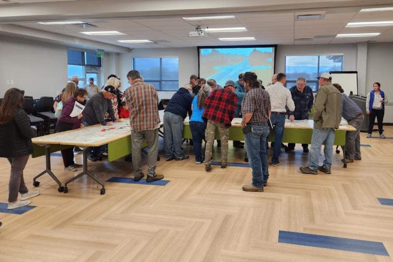 People walking around a table at open house.