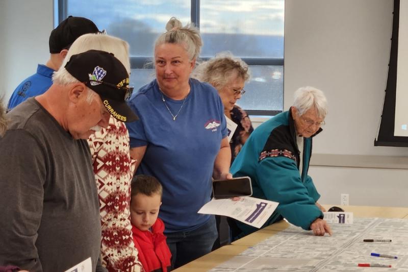 People stand around table looking at map.