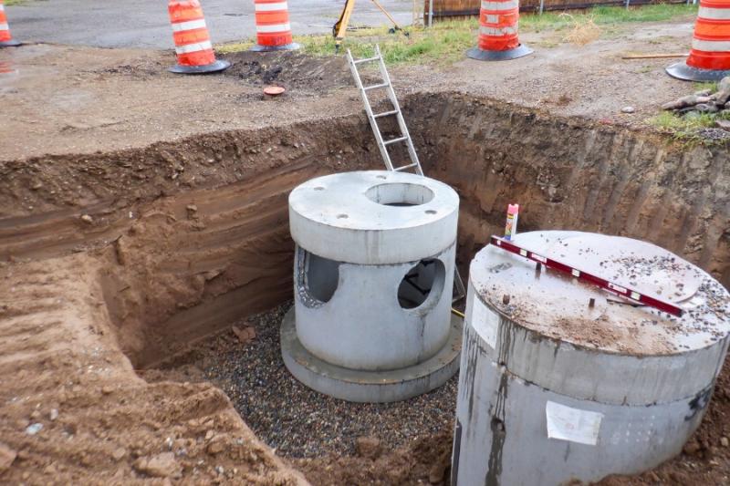 Two stormceptors in dirt hole surrounded by orange construction cones. 