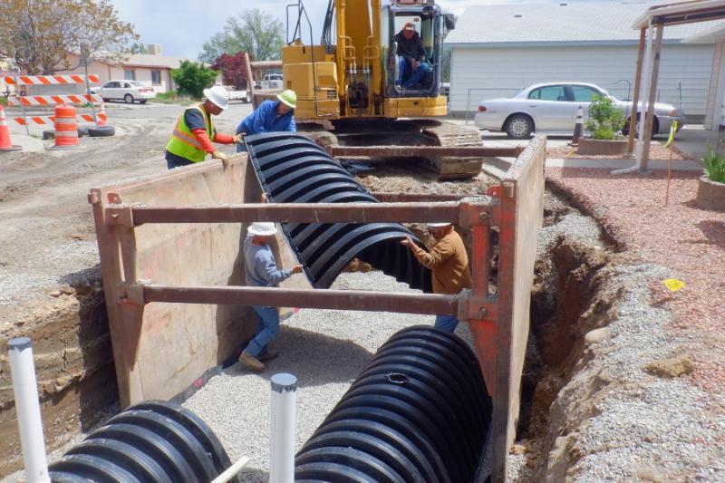 Four construction workers holding large black plastic material. 