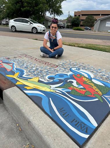 Mae Pina sitting next to her storm drain art.