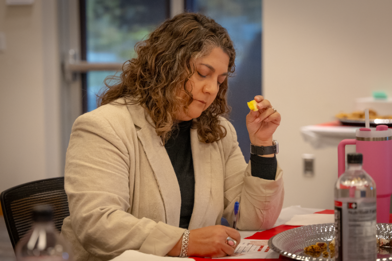 Woman holding cookie and writing on a piece of paper. 