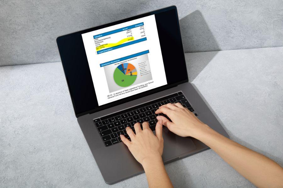 Hands typing on a laptop displaying a pie chart and numbers. 