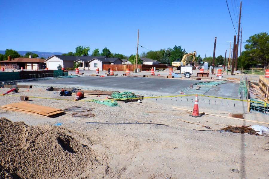 Unfinished concrete construction zone with caution tape and orange cones surrounding the area. 