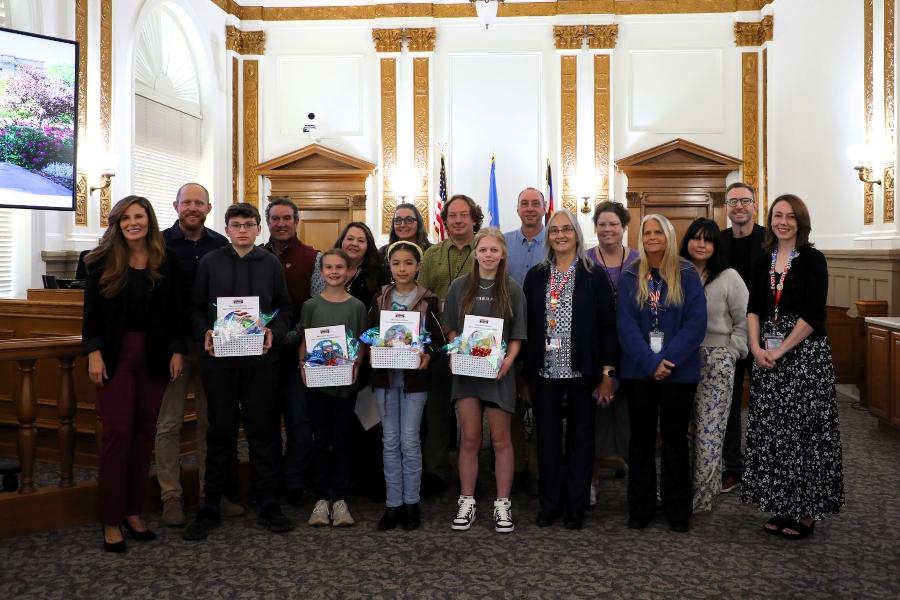A group of people smiling with kids in the front holding gift baskets. 