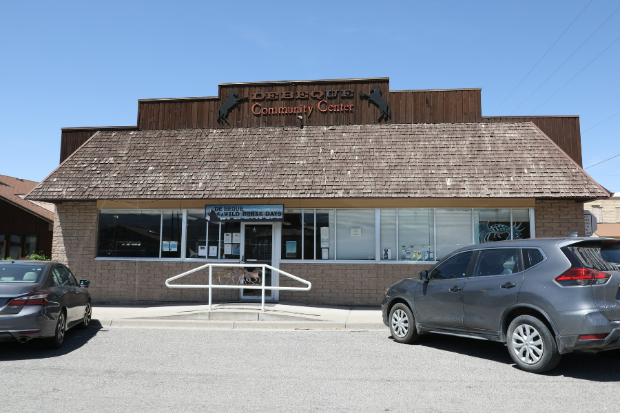 Exterior of the De Beque Community Hall at 381 Minter Ave., with vehicles parked in front.